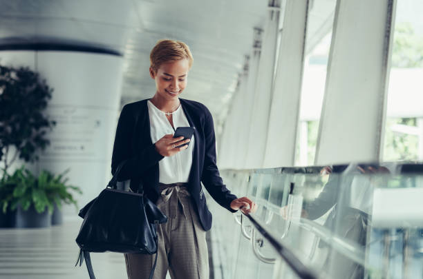 istock Happy business woman using mobile phone in modern corridor 1288870452