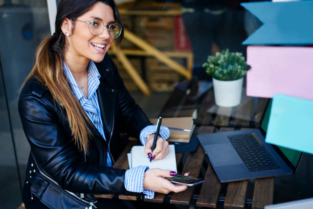 istock Cheerful female entrepreneur writing in notebook while working from cafe 1288871832