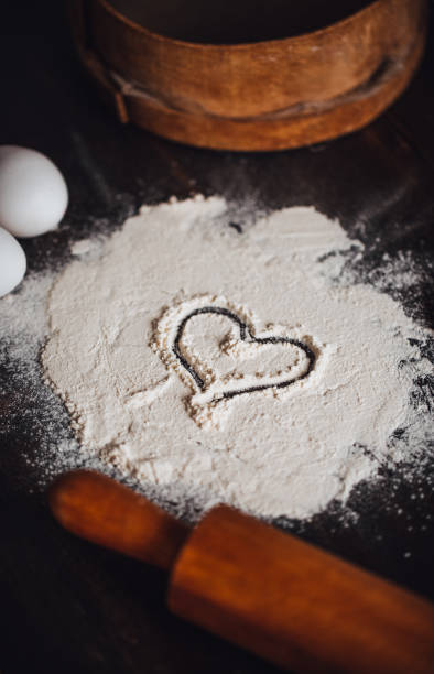 istock Making Heart Shape on the Flour on Rustic Wooden Table 1288872749