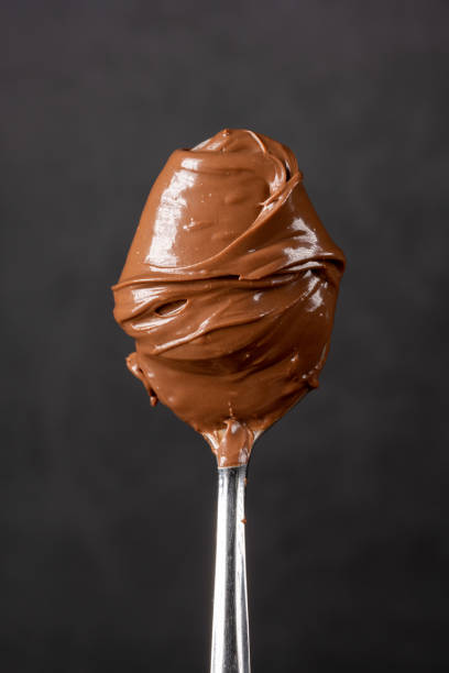 istock Cream chocolate in spoon on black background 1288875614