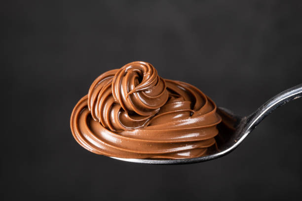 istock Cream chocolate in spoon on black background 1288875660