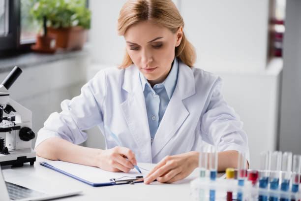 istock scientist writing on clipboard near microscope and test tubes on blurred background 1288878038
