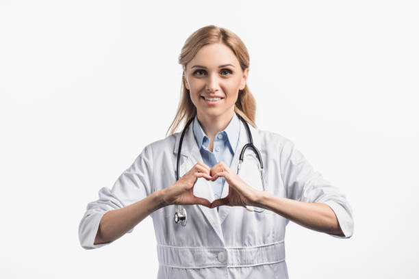 istock happy nurse in white coat smiling while showing hears sign with hands isolated on white 1288878276