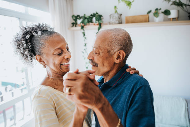 pareja mayor bailando en la habitación de casa abrazando y despreocupado - waltz fotografías e imágenes de stock