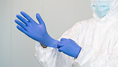 A healthcare worker prepares by putting on gloves to treat covid patients.