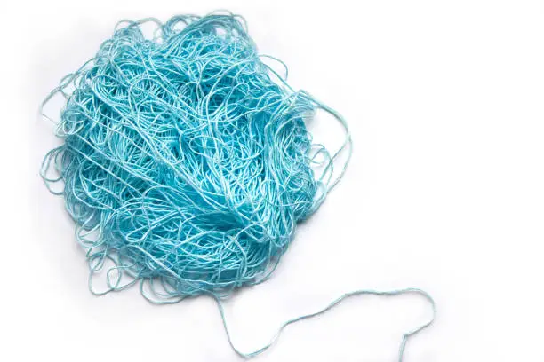 Photo of The concept of brainstorming. A tangle of mint, blue cotton threads, needlework yarn on a white background.