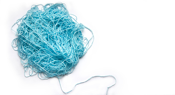 The concept of brainstorming. A tangle of mint, blue cotton threads, needlework yarn. Banner on a white background with space for text.