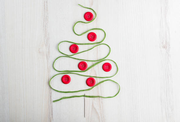 istock Sewing theme creative flat lay design: Christmas tree made of needle, thread and buttons on wooden surface 1288885373