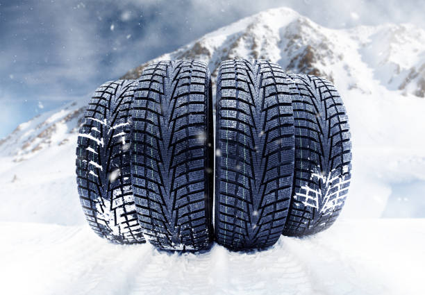 Stack of four wheel new black tyres on a snowy mountain background. Winter concept compilated image.