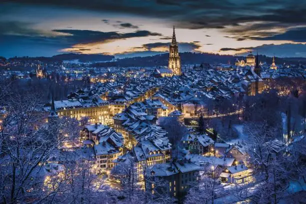 Beautiful winter evening sunset with snowy and illuminated buildings, Rosengarten, Bern, UNESCO, Switzerland
