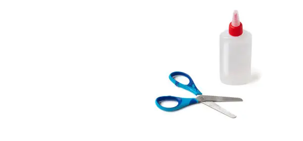 Children's scissors and a bottle of paper glue on a white background with space for text