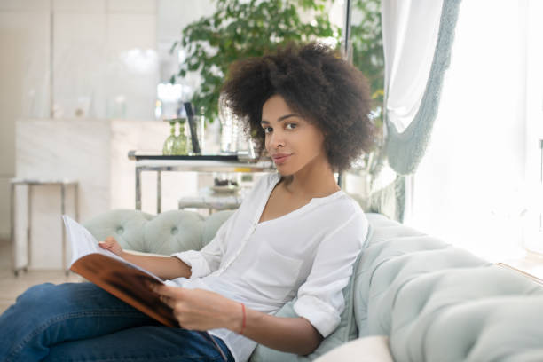 istock Pretty successful woman with magazine on sofa 1288893310