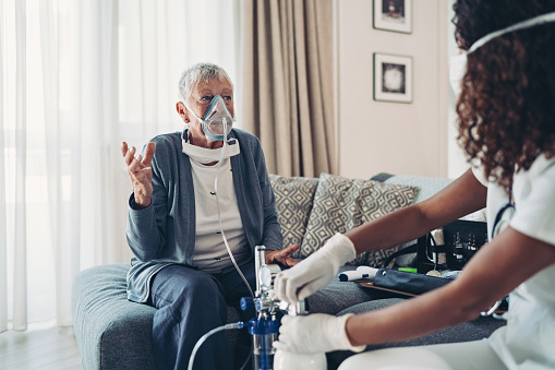 Mujer mayor con una máscara de oxígeno hablando con un médico photo