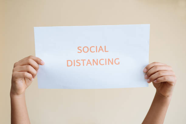 istock Hands holding a sign with a message about social distancing. Social distancing, keeping your distance in public society to protect. 1288894482