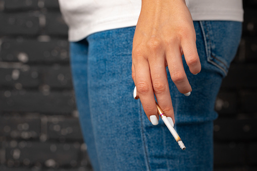 Female hand holding lighted cigarette close up photo