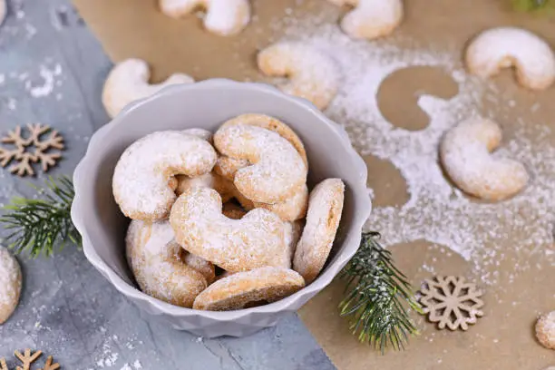 Seasonal crescent shaped christmas cookies called 'Vanillekipferl', a traditional Austrian or German Christmas biscuits with nuts and icing sugar in bowl