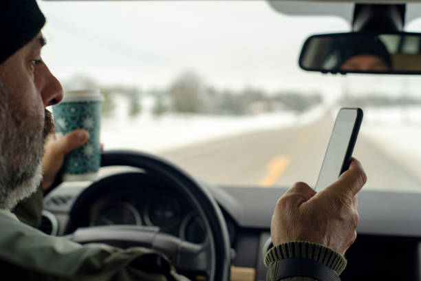 distraction au volant.  un homme conduisant tout en retenant un café et textos. - reckless driving photos et images de collection