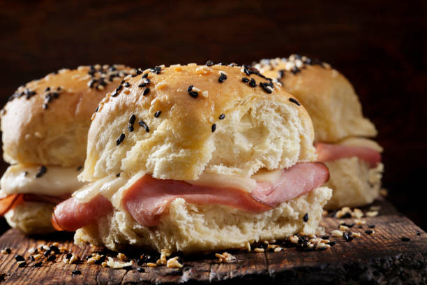 baked ham and swiss sliders on white tray buns - sesame bun american culture cheddar imagens e fotografias de stock