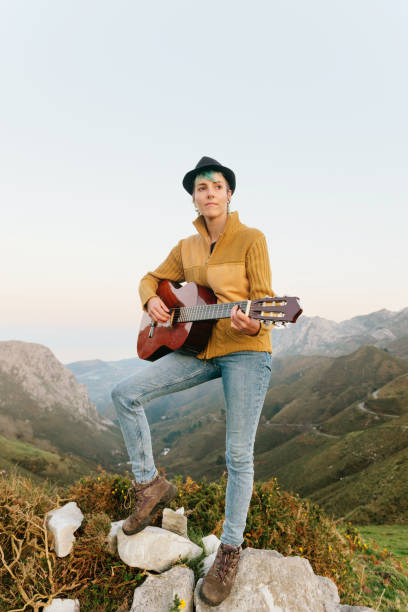 istock young woman playing guitar in the mountains 1288906183