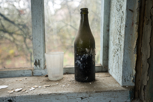 Old dusty soviet bottle inside house of abandoned village Zimovysche, post apocalyptic interior, Chernobyl zone, abandoned things