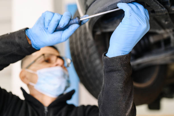 mecânico profissional com máscara facial protetora, consertando um carro na garagem de serviço. foto de alta qualidade - lubrication infection - fotografias e filmes do acervo