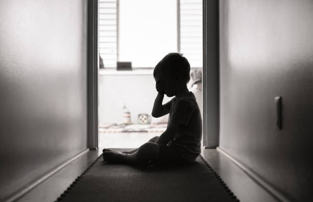 Depressed little boy sitting on the floor stock photo