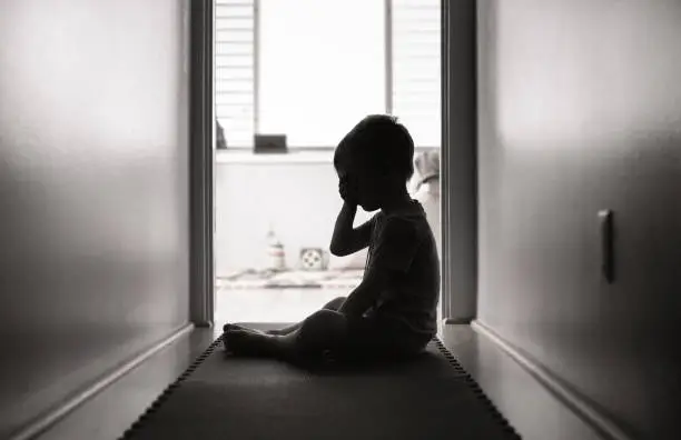 Photo of Depressed little boy sitting on the floor