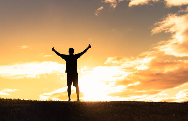 istock Man hiker with arms raised at sunset. 1288911362