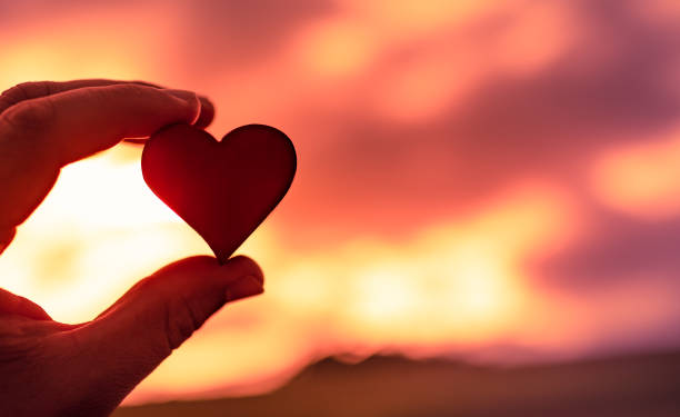 istock Hand holding heart against a sunset. 1288911809