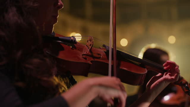 Cinematic close up shot of symphony orchestra with performers wearing medical protective masks playing violins