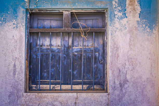 A charming blue wooden house featuring vibrant colored windows, set against a clear sky. This image captures unique architectural elements and peaceful ambiance.