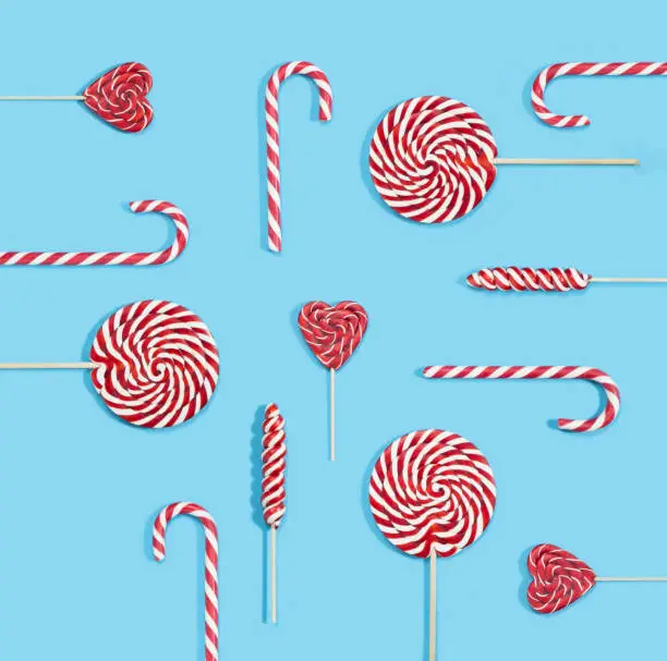 Christmas red candy canes and lollipops pattern on blue background. Merry Christmas sweets and Happy New Year concept.