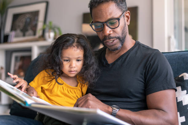 istock Affectionate father reading book with adorable mixed race daughter 1288920962