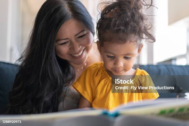 Adorable Mixed Race Toddler Reading Book With Her Mother Stock Photo - Download Image Now