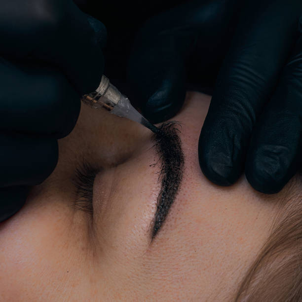 istock Permanent eyebrow makeup procedure. Eyebrow tattooing, process. The use of tools by a master for permanent eyebrow makeup. 1288921054