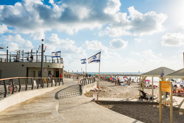 muitos turistas passam suas férias no mar mediterrâneo e agitando bandeira nacional israelense na praia de tel aviv, israel, no verão. - israel tel aviv skyscraper seascape - fotografias e filmes do acervo