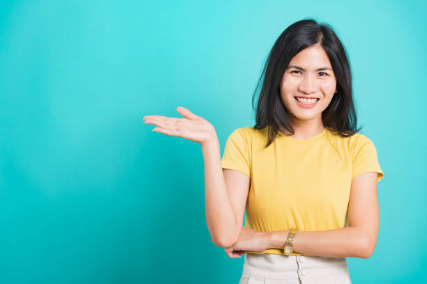 istock Young woman standing showing hand presenting product 1288927771