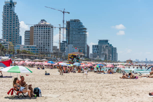 muitos turistas passam suas férias e muitos guarda-chuvas na praia de tel aviv, israel no verão. - israel tel aviv skyscraper seascape - fotografias e filmes do acervo