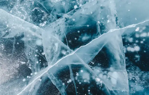 Photo of Beautiful cracks surface of the frozen lake of Baikal lake with frost methane bubbles in winter season.