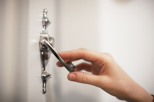 female hand knocking vintage door knocker, blurred background