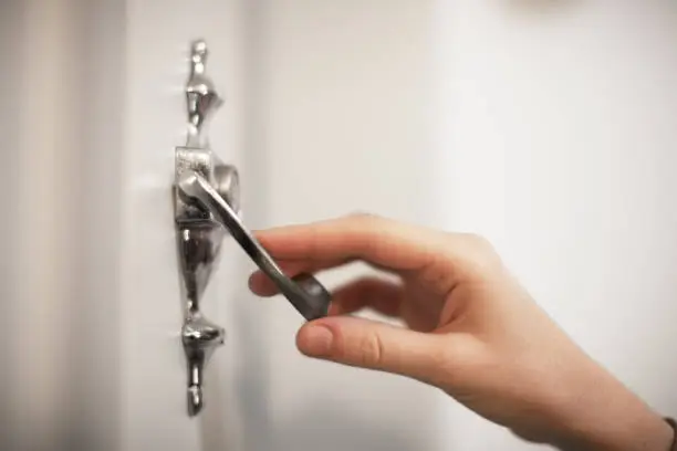 female hand use vintage metall door knocker selective focus