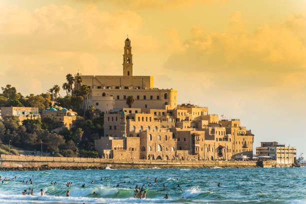 Old Jaffa city, old port and coastal line of Tel Aviv under sunset and lots of tourists are swimming and surfing at the Mediterranean sea. stock photo