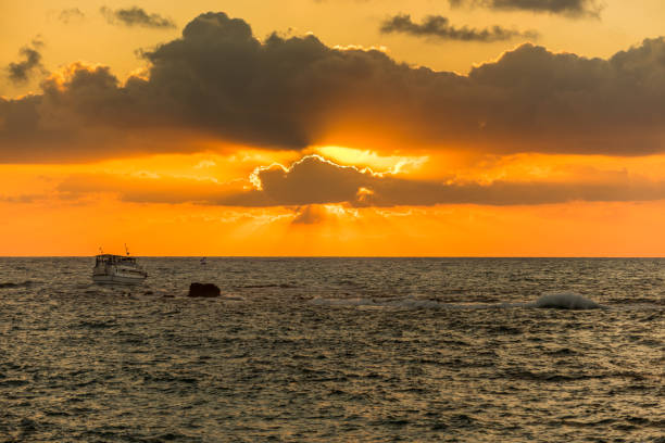 beautiful sunset and golden twilight, and clouds and a longly cruise ship sailing on the mediterranean sea in tel aviv, israel - sailboat sunset tel aviv sea imagens e fotografias de stock