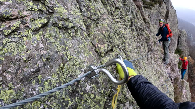 First person perspective of ascending 'via ferrata' on cloudy day
