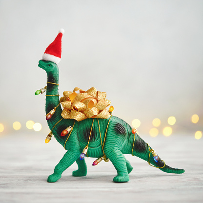 Christmas Background with Dinosaur Wrapped in Christmas Lights and Bow