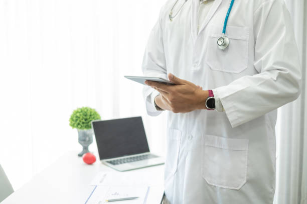 istock Close-up. Doctor man standing holding tablet at office. 1288938756