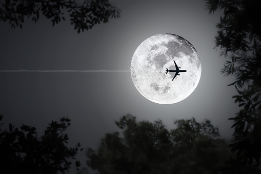 Midnight shiny full moon background for travel and transportation logistic at night flight with silhouette blurry leaves and  image of aircraft.Full moon from NASA https://www.nasa.gov/mission_pages/apollo/40th/images/apollo_image_25.html