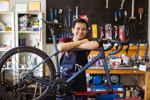 Repair technician bicycles was repaired gear bike shop.He is smiling