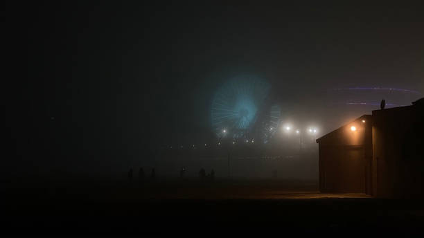 The lights of the Santa Monica pier glow through the fog rolling in at night