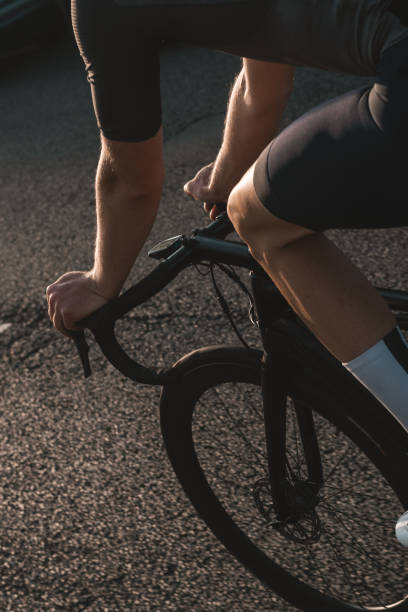 crop of cyclist's handlebars and front wheel during sunrise - road cycling imagens e fotografias de stock